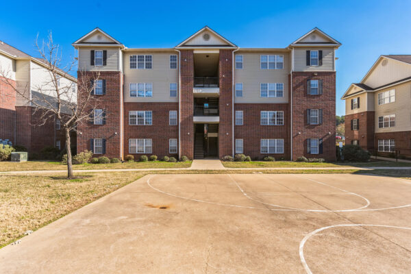 Brick exterior of student apartment building with basketball court at The Overlook near SFA Nacogdoches